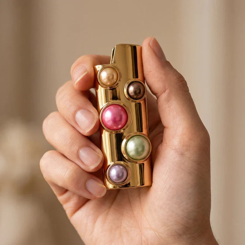 Porta-isqueiro para BIC grande dourado com pérolas coloridas segurado na mão para mostrar o tamanho