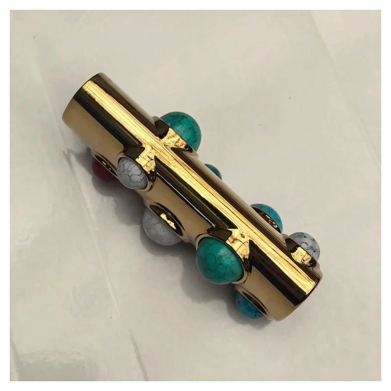 porta-isqueiro-bic-luxo-pedras-turquesa-capa - Porta-isqueiro BIC luxo dourado com pedras turquesa em angulo de capa; isqueiro nao incluso.